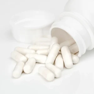 White capsules spilling from an unlabelled bottle