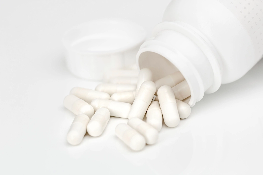 White capsules spilling from an unlabelled bottle