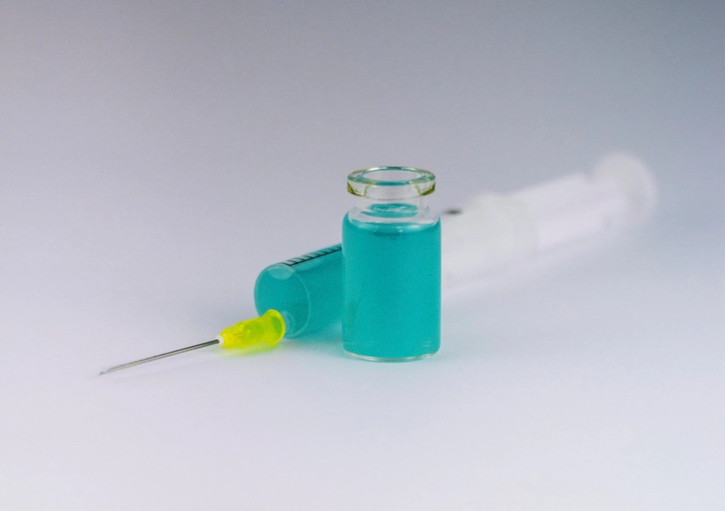 A glass vial and a syringe on a pale surface